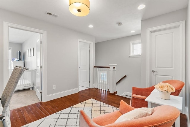 sitting room featuring recessed lighting, wood finished floors, visible vents, baseboards, and an upstairs landing