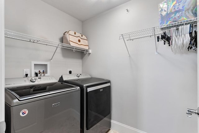 clothes washing area featuring laundry area, baseboards, and washer and clothes dryer