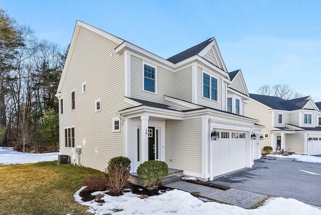 view of front of home featuring an attached garage, aphalt driveway, and cooling unit