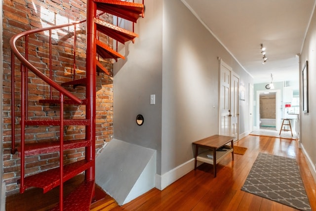 hallway with brick wall and hardwood / wood-style floors