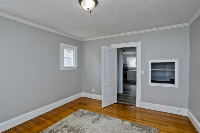 empty room featuring a textured ceiling, crown molding, and hardwood / wood-style flooring