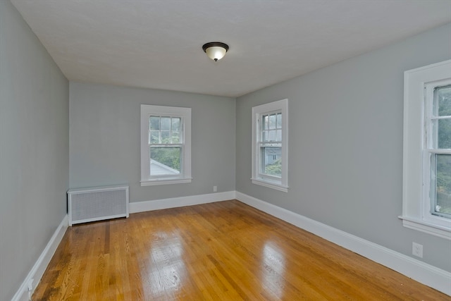 empty room featuring radiator heating unit and light hardwood / wood-style flooring