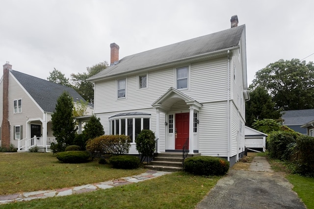 colonial-style house featuring a garage and a front lawn