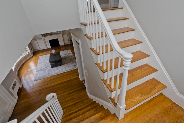 stairway featuring a fireplace and hardwood / wood-style floors