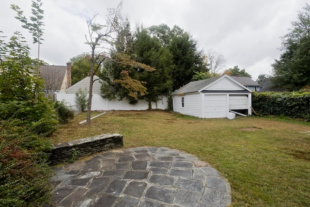 view of yard featuring a garage, a patio, and an outbuilding