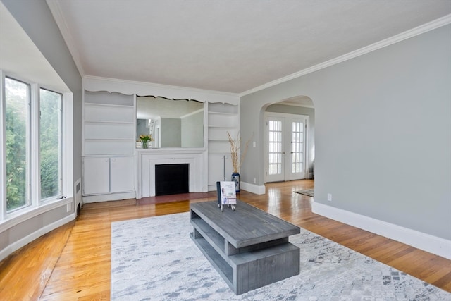 living room with french doors, ornamental molding, light hardwood / wood-style floors, and built in shelves