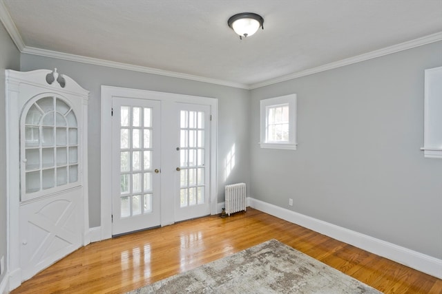 entryway with radiator heating unit, light wood-type flooring, ornamental molding, and french doors