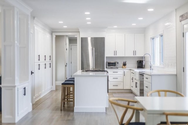 7 Colonial Dr, Chatham, MA 02633 - kitchen with a sink, stainless steel appliances, a center island, decorative backsplash, and white cabinets