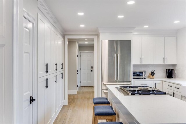 7 Colonial Dr, Chatham, MA 02633 - kitchen with appliances with stainless steel finishes, white cabinets, light countertops, a kitchen breakfast bar, and decorative backsplash