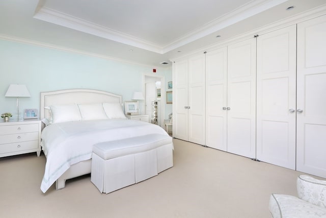 bedroom featuring crown molding, a raised ceiling, and light carpet