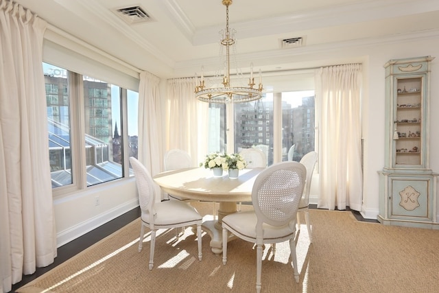 dining area with an inviting chandelier, ornamental molding, and a tray ceiling