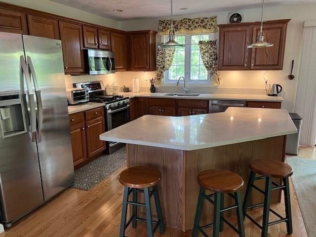 10 Atherton Rd, Hudson, MA 01749 - kitchen featuring stainless steel appliances, a sink, a breakfast bar area, and light countertops