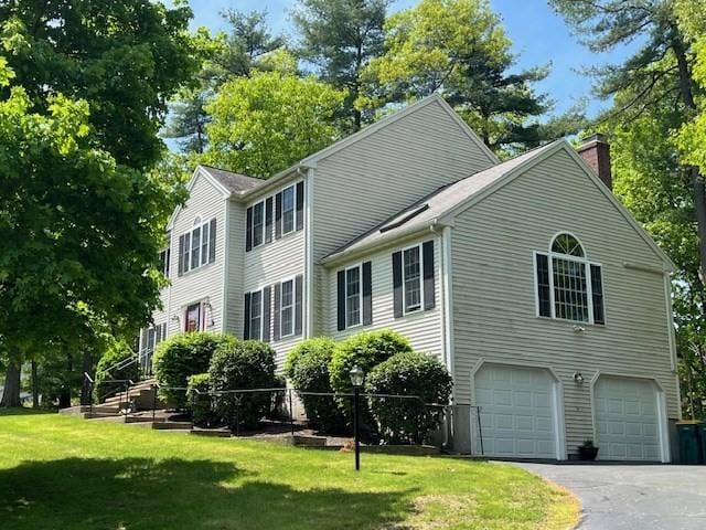 10 Atherton Rd, Hudson, MA 01749 - view of side of property featuring a garage, a chimney, a lawn, and asphalt driveway