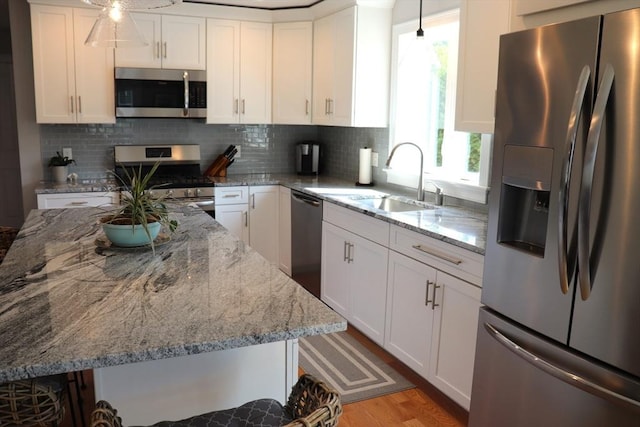 kitchen featuring white cabinets, stainless steel appliances, light wood-type flooring, and a sink