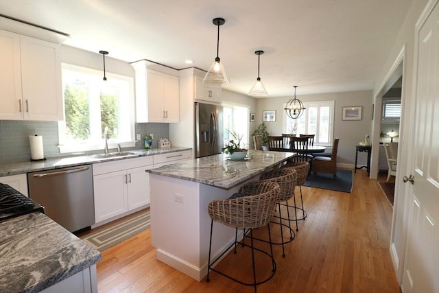 kitchen featuring light wood-style flooring, white cabinets, stainless steel appliances, and a sink