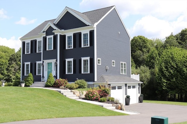 colonial-style house featuring concrete driveway, a garage, and a front yard