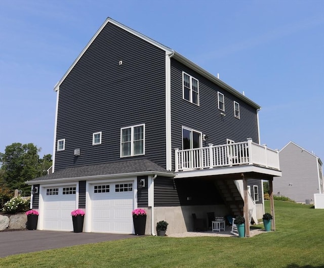 rear view of house featuring a deck, a yard, a garage, and driveway