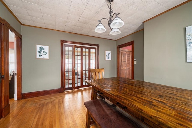 dining area featuring baseboards, a notable chandelier, crown molding, and hardwood / wood-style floors