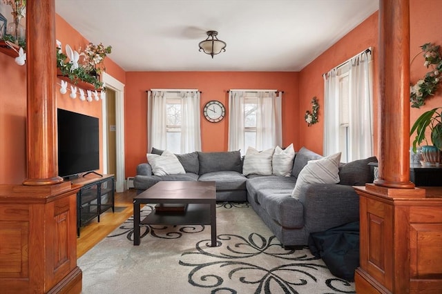 living room with light wood-style flooring and ornate columns