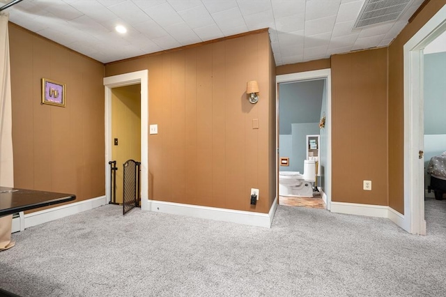 unfurnished bedroom featuring carpet floors, visible vents, baseboards, and ensuite bathroom