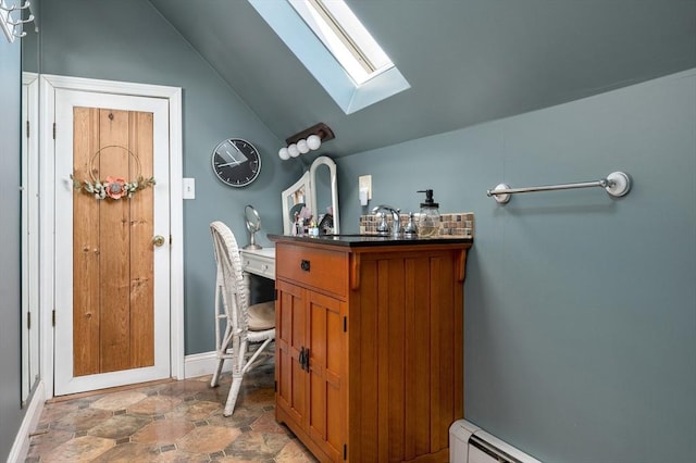 bar with lofted ceiling with skylight, a baseboard radiator, stone finish floor, and baseboards