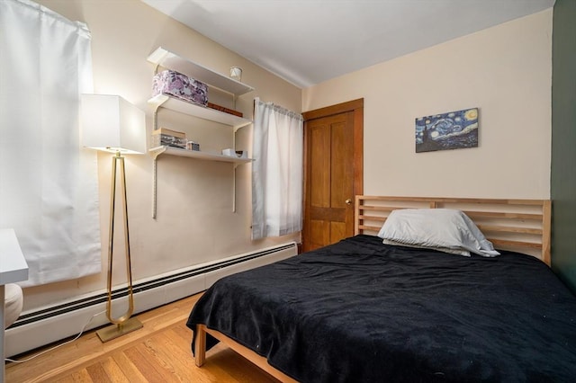 bedroom featuring a baseboard heating unit and wood finished floors