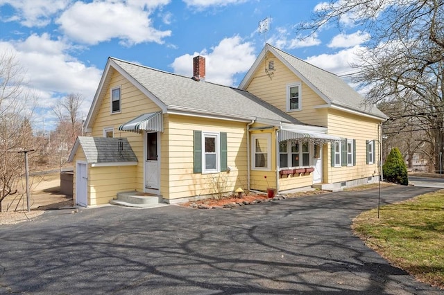 view of front of property featuring aphalt driveway, roof with shingles, and a chimney