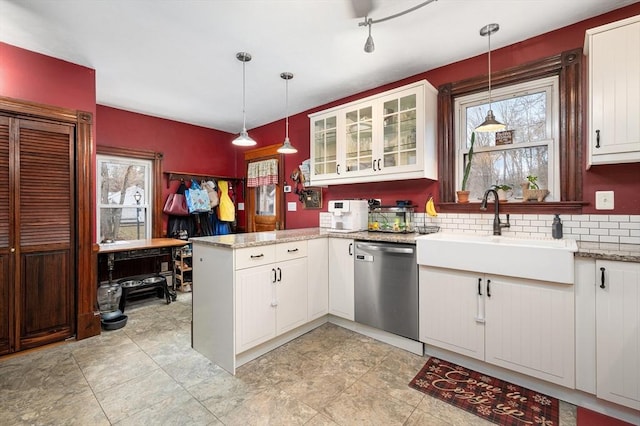 kitchen featuring white cabinetry, a sink, a peninsula, and stainless steel dishwasher