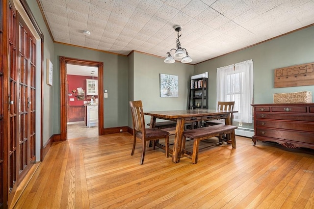 dining area with light wood-style floors, baseboards, ornamental molding, and a chandelier