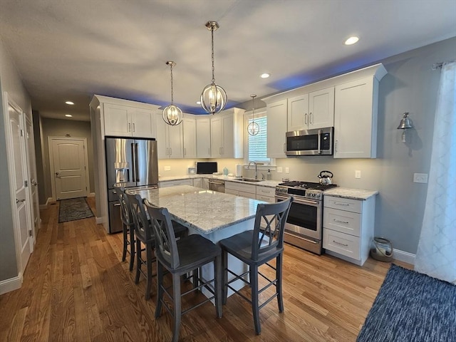 38 John Perkins Way, Middleboro, MA 02346 - kitchen with stainless steel appliances, a breakfast bar, a sink, light stone countertops, and white cabinets