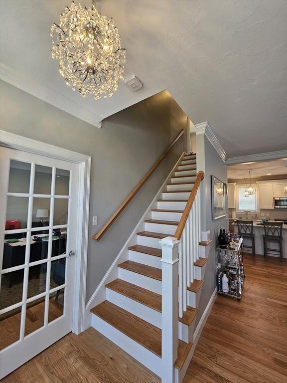 38 John Perkins Way, Middleboro, MA 02346 - stairway featuring crown molding, a chandelier, wood finished floors, and baseboards
