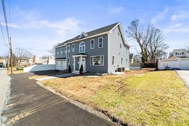 view of front of house with central AC unit, driveway, and fence