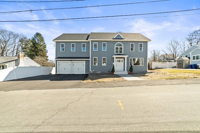 view of front of property with a garage, aphalt driveway, and fence