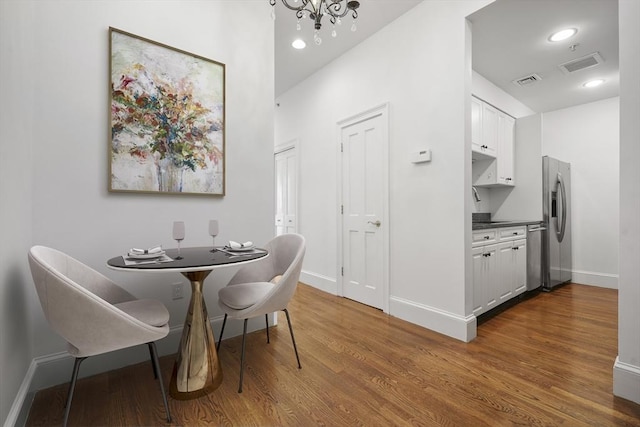 dining room with hardwood / wood-style flooring, sink, and an inviting chandelier