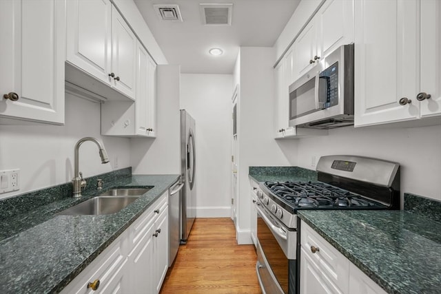 kitchen with white cabinetry, sink, stainless steel appliances, and light hardwood / wood-style flooring