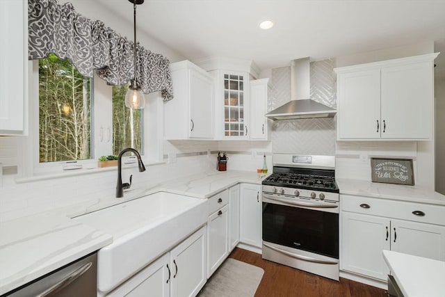 kitchen featuring tasteful backsplash, wall chimney exhaust hood, stainless steel appliances, and a sink