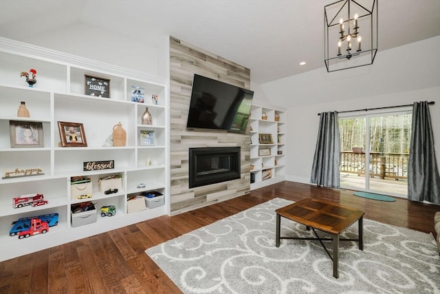 living area with built in features, a notable chandelier, lofted ceiling, wood finished floors, and a tile fireplace