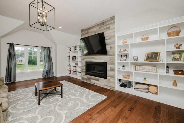 living room with vaulted ceiling, wood finished floors, built in shelves, a fireplace, and a notable chandelier