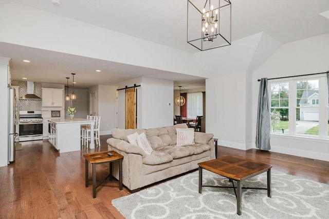 living area with a barn door, a notable chandelier, baseboards, and dark wood-style flooring