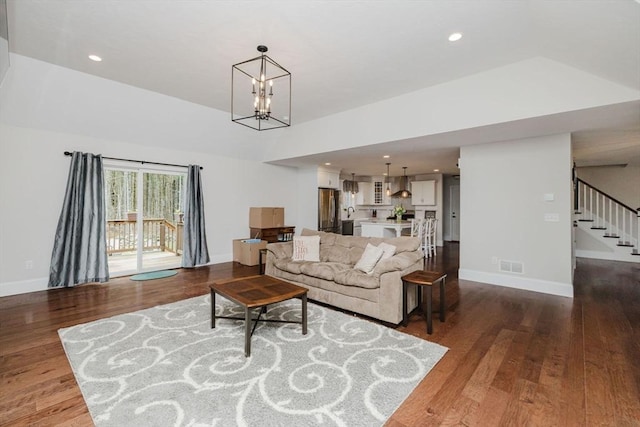 living area featuring baseboards, visible vents, a notable chandelier, wood finished floors, and stairs