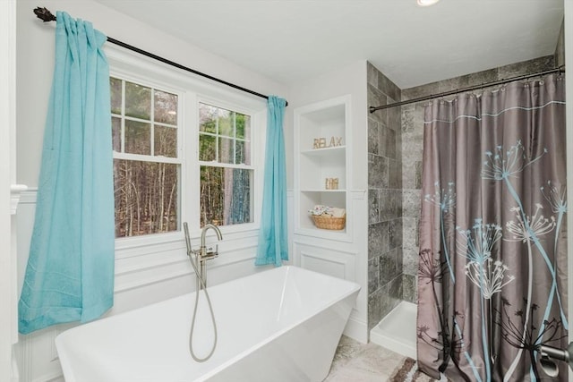 bathroom featuring a freestanding tub, built in shelves, and tiled shower