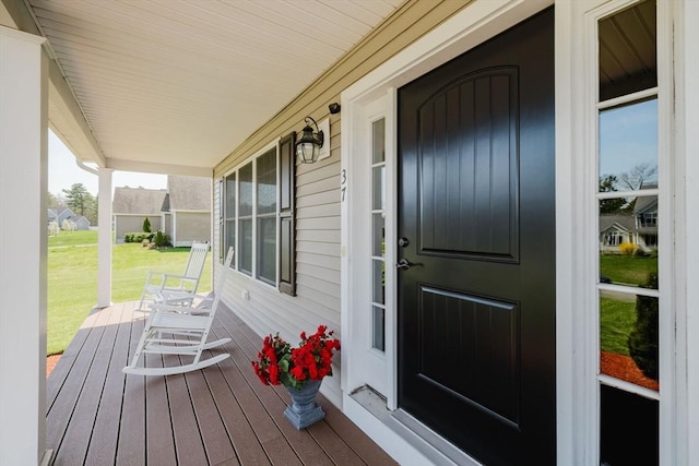 doorway to property with a lawn and a porch
