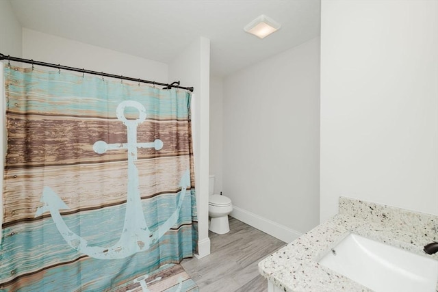 bathroom with wood finished floors, vanity, a shower with curtain, baseboards, and toilet