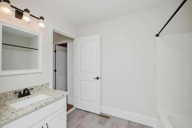 full bath featuring bathtub / shower combination, visible vents, baseboards, wood finished floors, and vanity