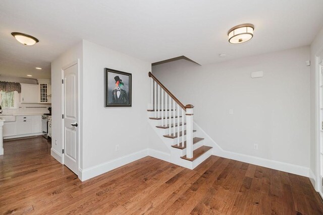 staircase with baseboards, wood finished floors, and recessed lighting
