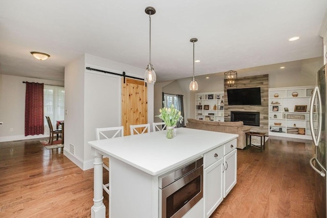 kitchen featuring light wood finished floors, stainless steel appliances, white cabinetry, and a barn door