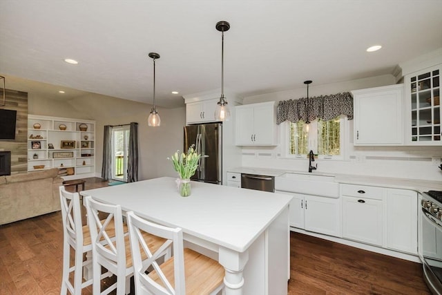 kitchen featuring stainless steel appliances, a sink, open floor plan, and plenty of natural light