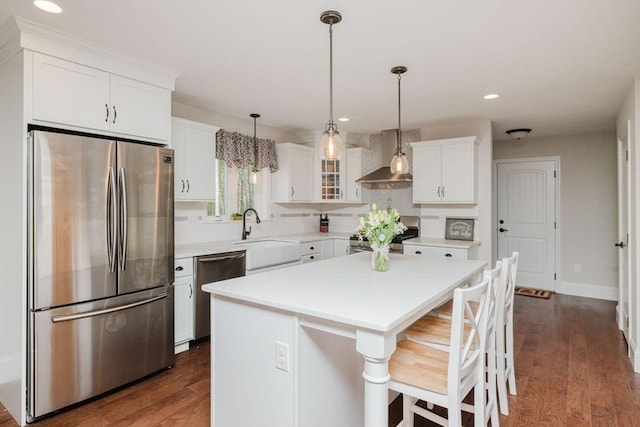 kitchen featuring wall chimney range hood, white cabinetry, stainless steel appliances, and a sink