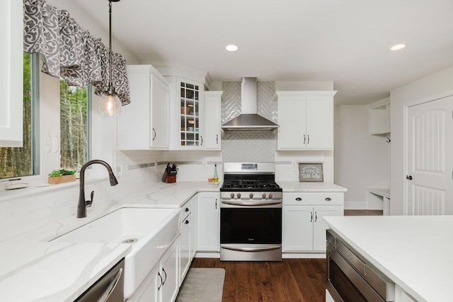 kitchen featuring stainless steel range with gas cooktop, dark wood-style floors, a sink, backsplash, and wall chimney range hood