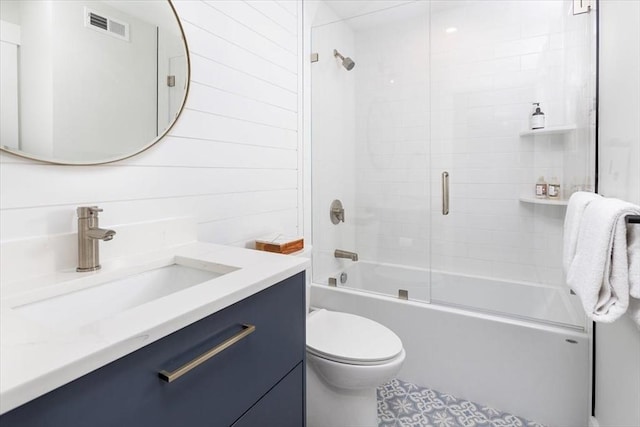 bathroom with toilet, enclosed tub / shower combo, and vanity